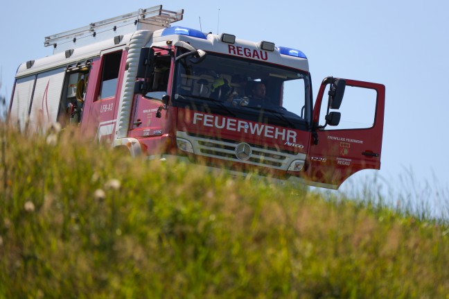 LKW-Bergung in Regau: LKW mit Putzsilo gegen Hausfassade gekippt