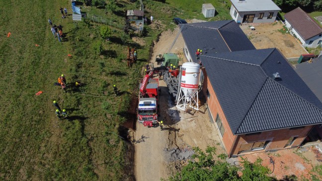 LKW-Bergung in Regau: LKW mit Putzsilo gegen Hausfassade gekippt