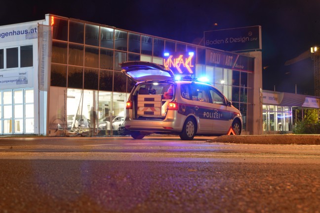 Auto kracht bei Verkehrsunfall in Linz-Industriegebiet-Hafen in Schauraum eines Autohauses