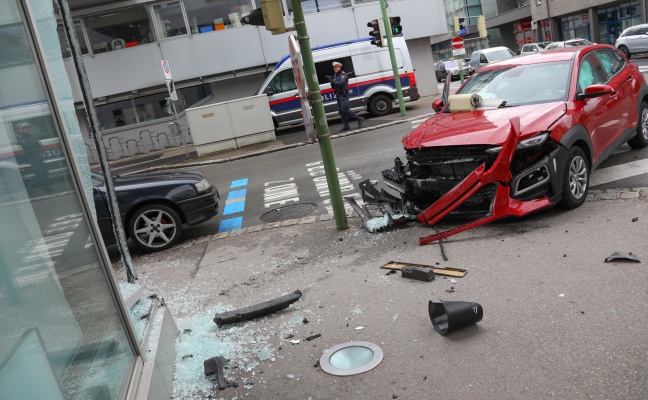 Unfallfahrzeug kracht nach Kreuzungscrash in Wels-Innenstadt gegen Glasfassade eines Gebudes