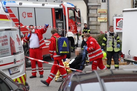 Auto fhrt in St. Florian vor Stift in Personengruppe und Marktstand