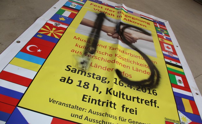 Plakat und Schaukasten in Alkoven mit "IS"-Schriftzug besprüht